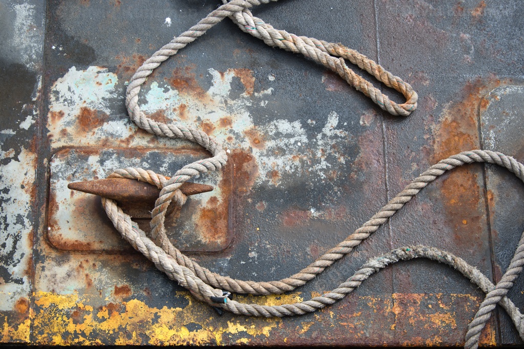 A rope strewn across a well travelled and worn dock.