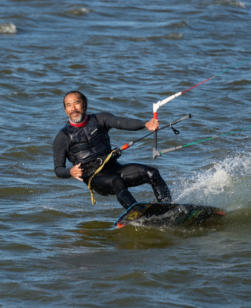 Photographs of kitesurfers having fun and performing various tricks on a clear, beautiful day.