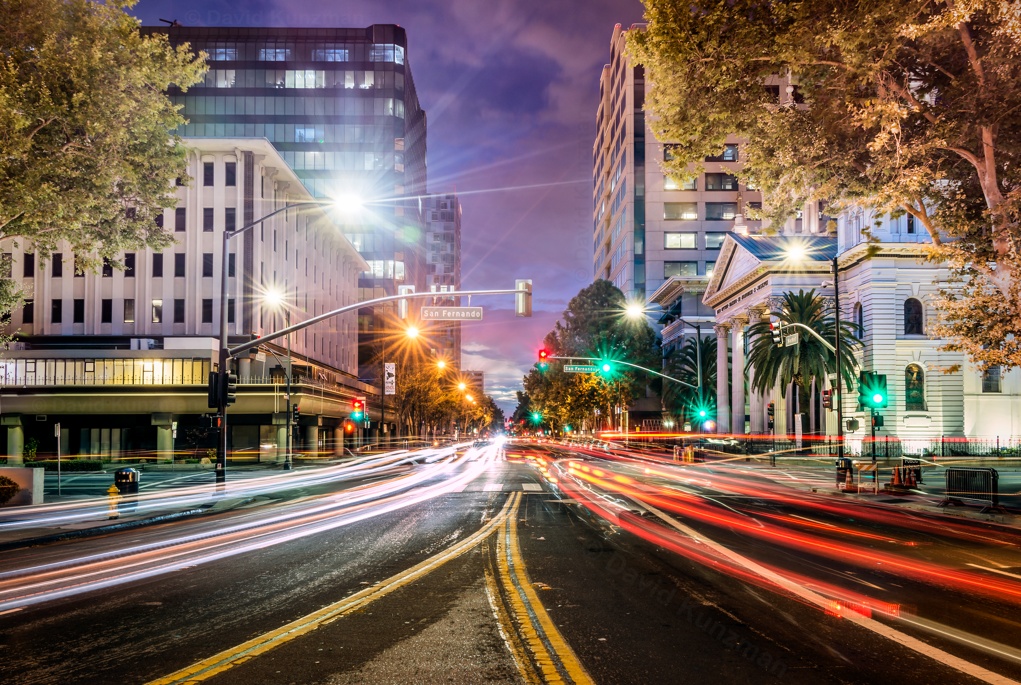 A long exposure photograph looking down Market Street in downtown San Jose.  Car headlights and taillights are stretched out, creating streak along the road, on either side of the camera's view.