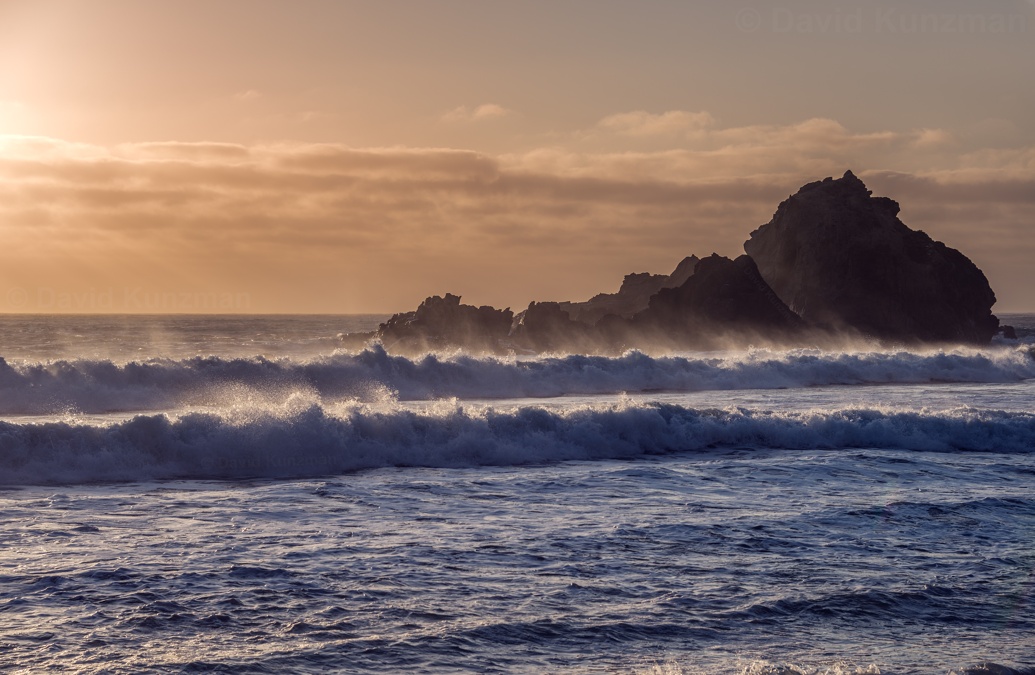 A photograph of waves crashing along Pfeiffer Beach, California as they roll in from the Pacific Ocean shortly before sunset.